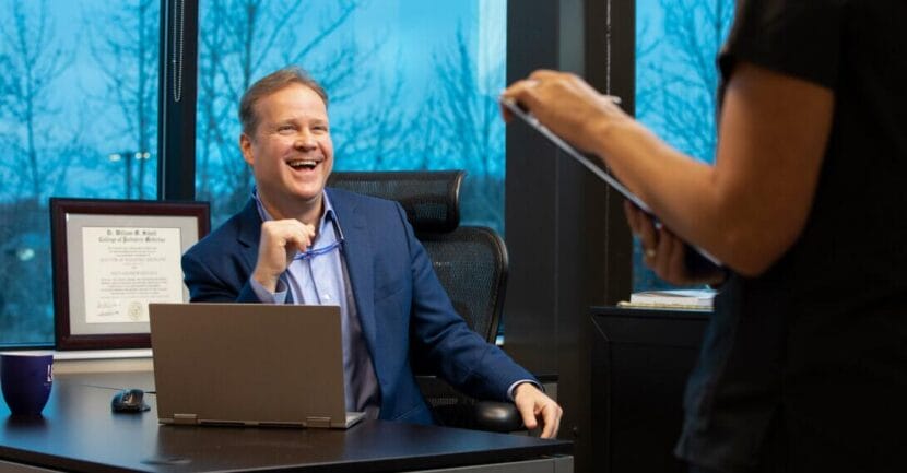 man sitting at desk in medical office laughing