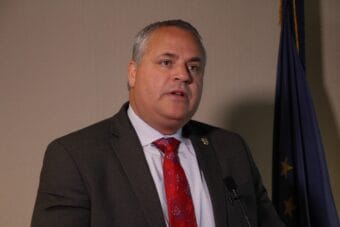 a man with gray hair and a red tie speaks