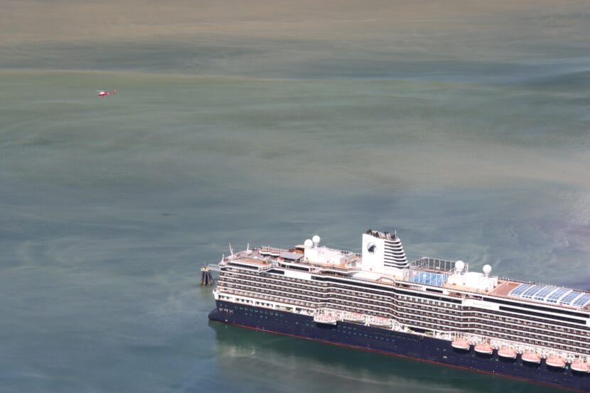 Smoke can be seen rising from the stack of a large cruise ship