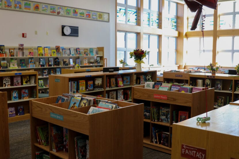 Numerous wooden shelves full of graphic novels and fiction books.