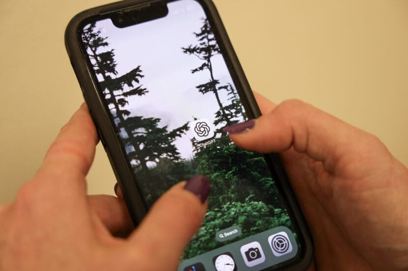 Two hands with dark purple nail polish hover over the app icon for ChatGPT on an iPhone.