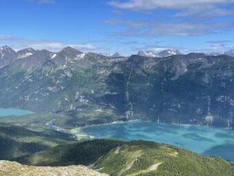 A view from a high hill looking across a copper-colored body of water toward steep mountains on the other side.