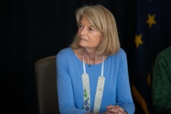 A woman in a blue shirt attends a press briefing.