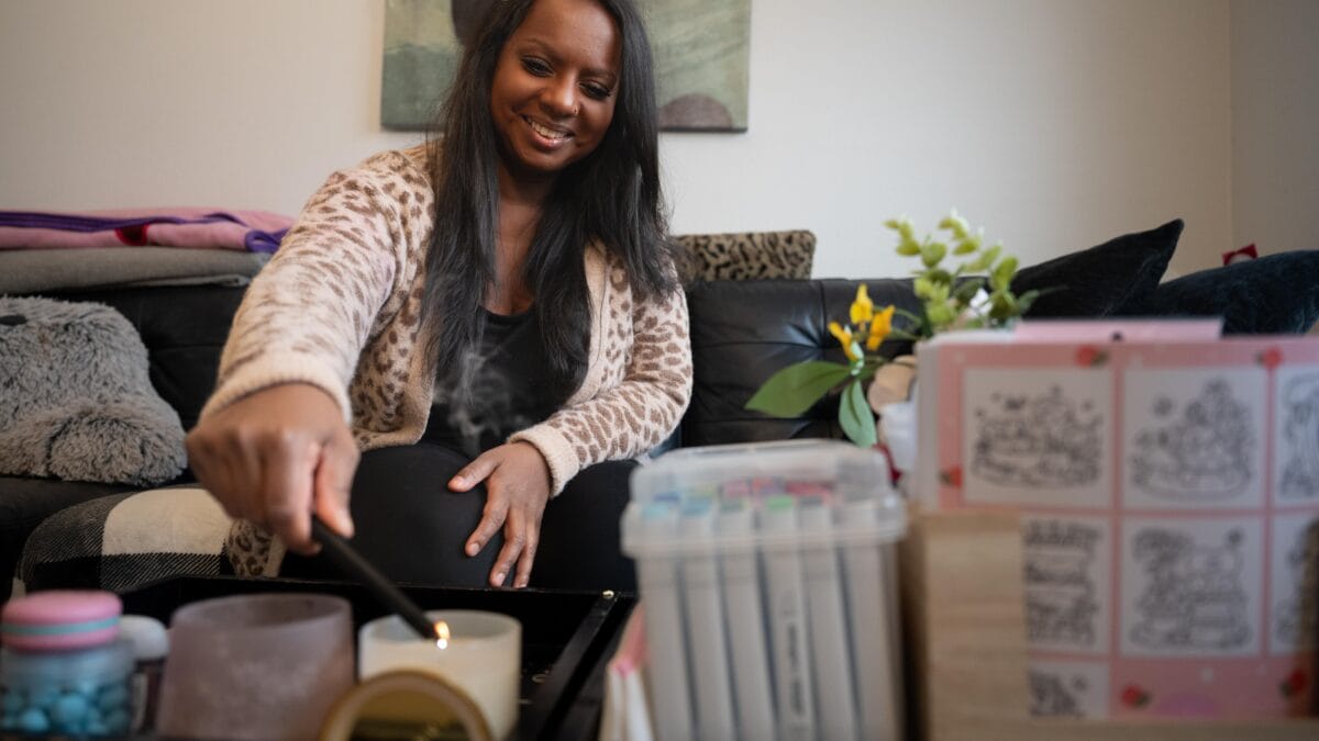 A woman in a sweater lights a candle.