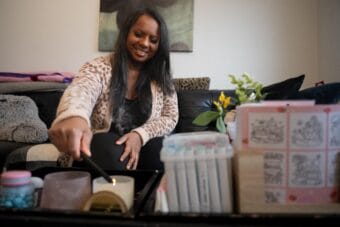 A woman in a sweater lights a candle.