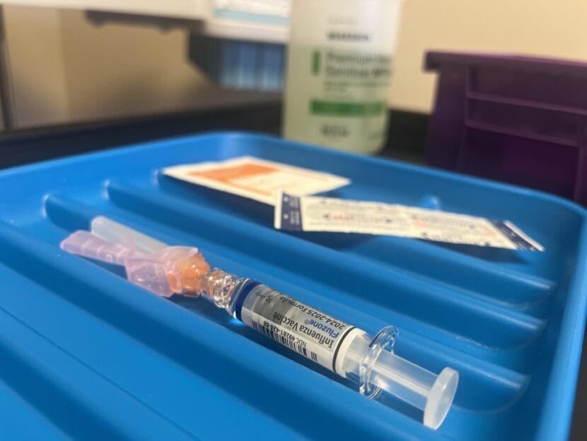 A syringe, bandage and alcohol pad lie on a blue plastic tray. 