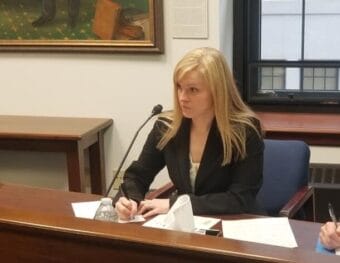 A woman sits at a desk and writes on paper.