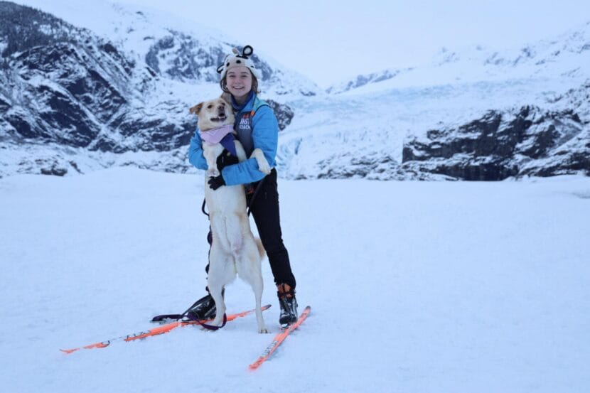 KTOO reporter Clarise Larson and her dog, Bloon, in front of the Mendenhall Glacier in February 2023.
