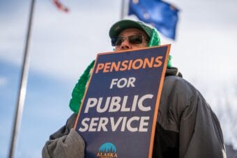 A man holds a sign supporting public-sector pension legislation during a union demonstration at the Alaska State Capitol on Feb. 14, 2025.
