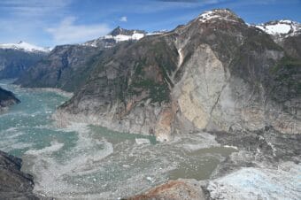 Aerial photo of the Aug. 10, 2025 Tracy Arm landslide showing the terminus of South Sawyer Glacier and Tracy Arm, taken during a U.S. Geological Survey overflight on Aug. 13, 2025. Note the trimline along the far side of the fjord, caused by the tsunami stripping the walls of vegetations.