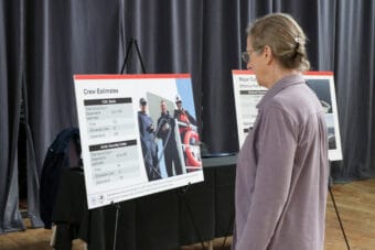 a woman in a gray shirt reads a poster with information about the icebreaker Storis.