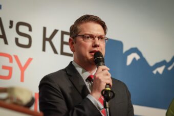 A man in a suit speaks in a microphone.
