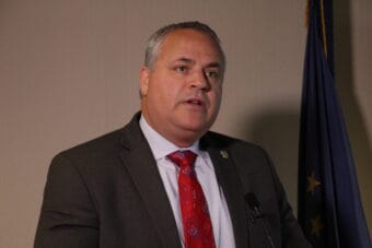 a man with gray hair and a red tie speaks