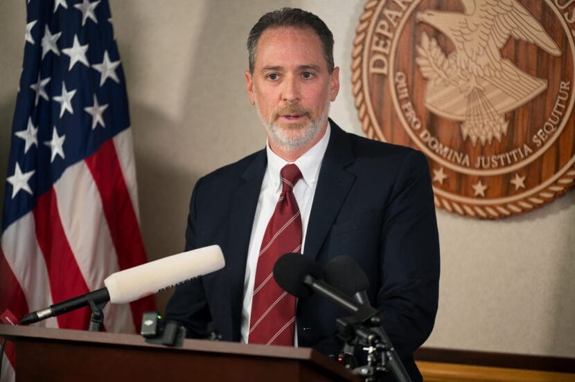 A man in a suit speaks at a podium.