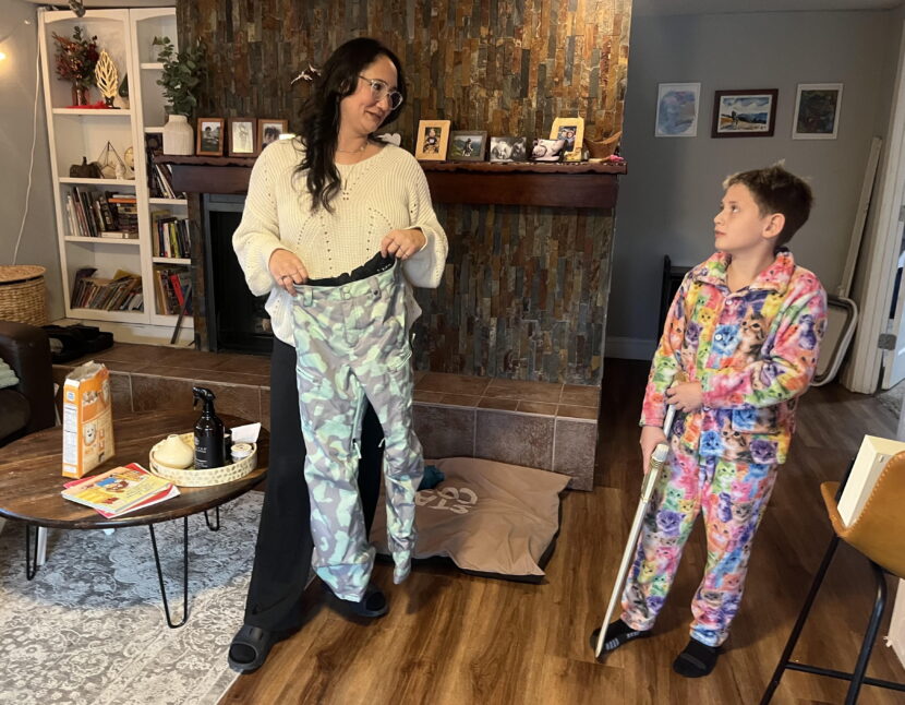 Naomi Estes holds up the like-new name-brand snow pants she recently found for her son Wesley (right) at Goodwill. It was exactly what she was looking for, she said.